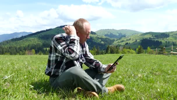 4k. Vuxen man använder handdator på berg kulle i solig dag — Stockvideo