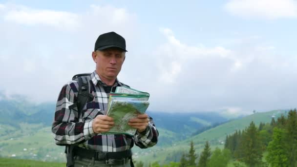 4K. Squadra turistica zaino in spalla. L'uomo adulto sulle montagne cerca la strada attraverso la mappa cartacea — Video Stock