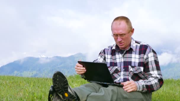 4 k toeristische volwassen mens in Bergen werken draagbare computer. Gezicht in glazen — Stockvideo