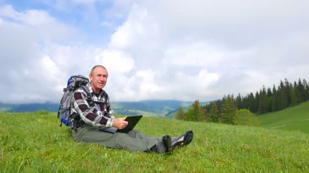 4K turista uomo zaino in spalla in montagna con computer portatile ricevuto buone notizie — Video Stock