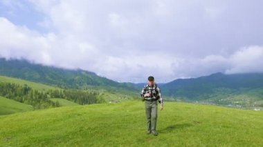 4k. Dağlarda siyah şapkalı adam backpacker dürbün görünüyor 