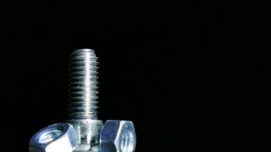 Üç somun ve cıvata döner koyu arka planı. 4 k makro