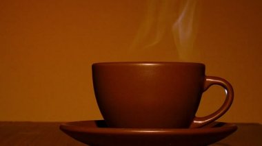 Kahverengi fincan sıcak kahve ya da çay buharla turuncu tonda. 4k vurdu