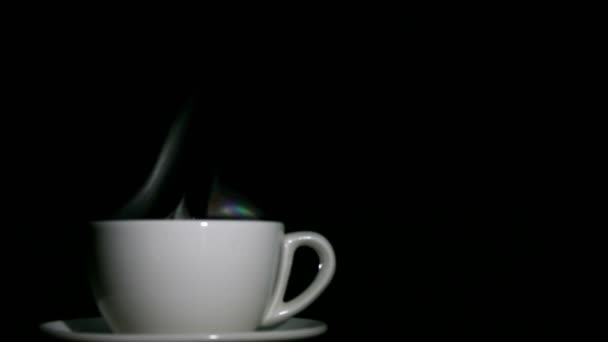Weiße Tasse Tee oder Kaffee mit Dampf auf schwarzem Hintergrund. 4k linke Seite — Stockvideo