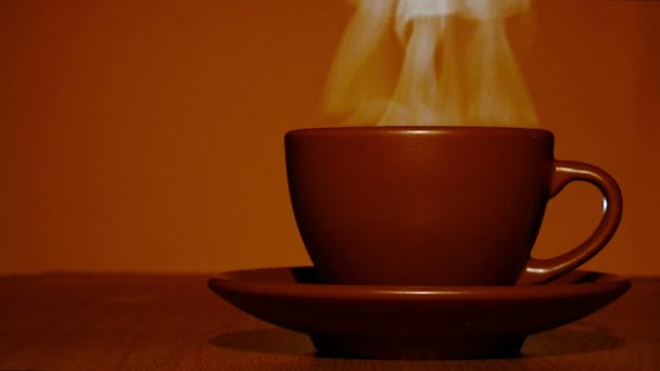 Καφέ φλιτζάνι ζεστό καφέ ή τσάι με ατμό σε πορτοκαλί τόνος. 4k πυροβόλησε — Αρχείο Βίντεο