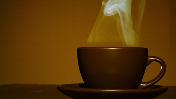 Коричневая чашка горячего кофе или чая с паром оранжевого цвета. 4К выстрел — стоковое видео
