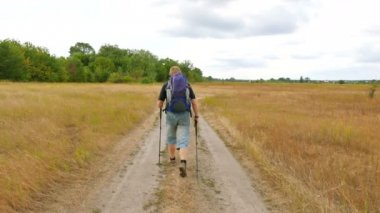 Adam turist stokları ile kırsal yolda yürürken. 4k 3840 x 2160