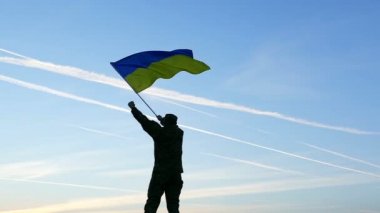   Asker dalgalar Ukrayna bayrağı karşı gündoğumu turuncu gökyüzü. Ağır çekim 