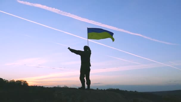 Soldado Ondas Bandeira ucraniana contra o nascer do sol céu laranja. Movimento lento — Vídeo de Stock