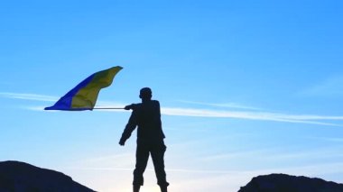  Ukrayna bayrağı ve askerin siluet mavi gökyüzü karşı dalgalar. Ağır çekim 