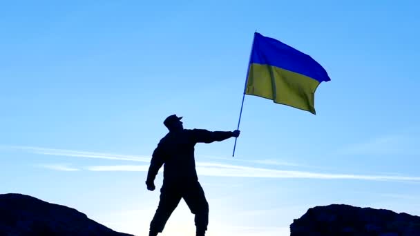 Soldado sostiene bandera ucraniana contra el cielo azul. — Vídeos de Stock