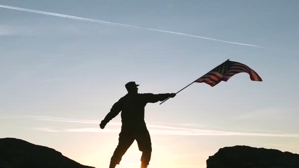 Voják drží Americká vlajka proti východu slunce oranžové obloze. Zpomalený pohyb — Stock video