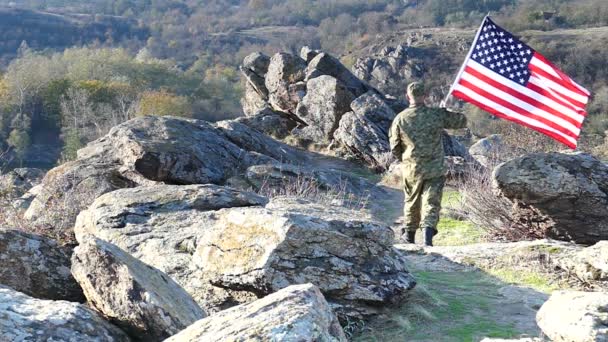 Солдат с американским флагом идет по горной тропе. Slow Motion — стоковое видео