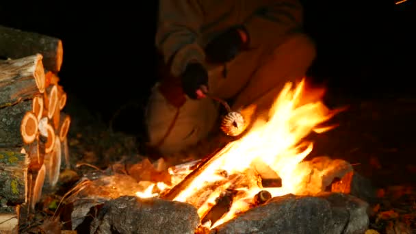 4K .Man Malvaviscos tostados en el fuego del campamento — Vídeo de stock