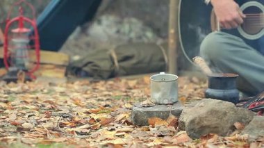  Adam turist kamp ateşi yanında gitar çalıyor. Sonbahar Seyahat hayat. Vintage ateş.