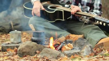  Adam turist gitar ile kamp ateşi üzerinde kahve yapıyor. Seyahat yaşam. Vintage ateş.