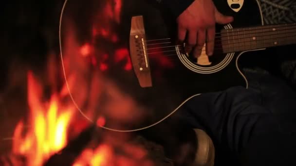 Man tourist grać na gitarze w pobliżu ogniska. Podróż życia. Odbicie ogień na gitarze — Wideo stockowe
