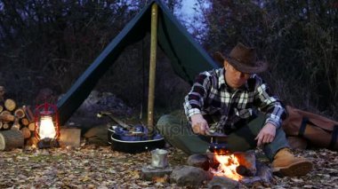 4k. Şenlik ateşi yakınındaki kovboy şapkalı adam kahve yapayım. Sonbahar Seyahat hayat. 