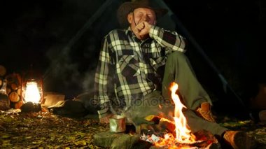 4k. Bir erkek, kovboy şapkası şenlik ateşi yakınındaki uyku gider. Seyahat hayat. 