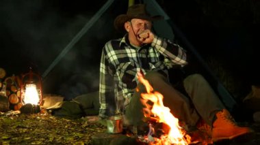 4k. Bir erkek, kovboy şapkası şenlik ateşi yakınındaki uyku gider. Seyahat hayat. 