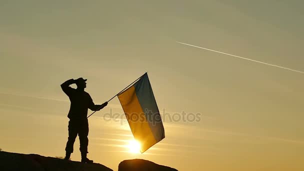Солдат приветствует украинский флаг, время восхода солнца в медленном движении — стоковое видео
