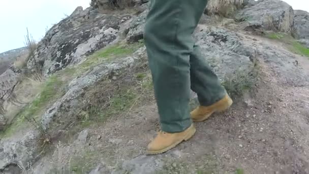 Mannelijke benen in gele laarzen naar beneden op het spoor in de heuvel. — Stockvideo