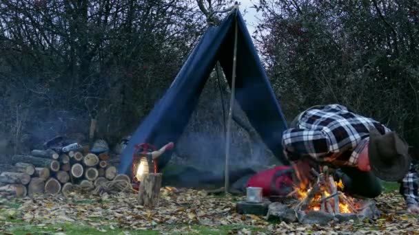 4K. L'uomo col cappello da cowboy gonfia il falò. Autunno vita di viaggio . — Video Stock