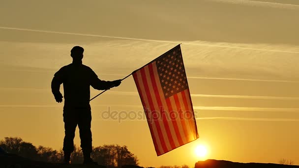 Soldat schwenkt amerikanische Flagge gegen orangen Himmel. Zeitlupe aus nächster Nähe — Stockvideo