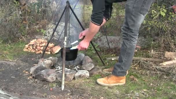 Приготування їжі на відкритому повітрі. Чоловік готує на багатті — стокове відео