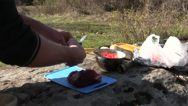 Приготування їжі на відкритому повітрі. Чоловік ріже м'ясо — стокове відео