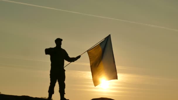 4K. Soldado silueta saludo Bandera de Ucrania, la hora del amanecer — Vídeos de Stock