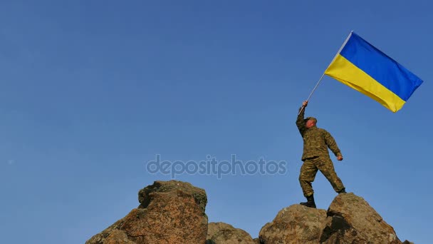 4K. Soldat silhouette vagues drapeau ukrainien, contre ciel bleu — Video