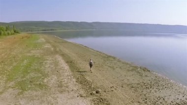  Hava. Bir adam turistik göl kıyı şeridi üzerinde gider. 