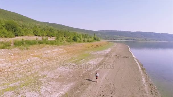 Aéreo. Homem viajante vai na costa do lago. Hora de verão — Vídeo de Stock