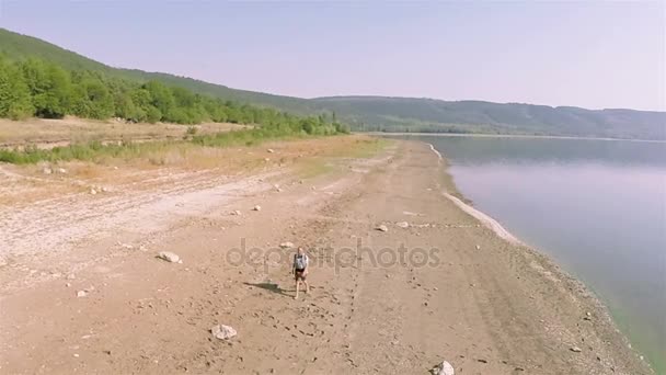 Aereo. Un uomo viaggiatore va sulla costa del lago. Volo circolare — Video Stock