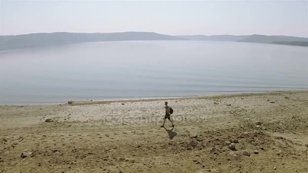 Luchtfoto. Een Man reiziger aan kust van lake gaat. Circulaire vlucht — Stockvideo