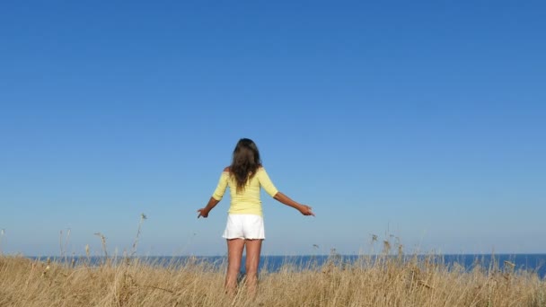 4k. Frau in gelber Bluse hebt die Hände gegen das Meer. Fokusansatz — Stockvideo
