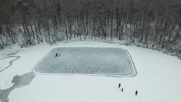 4k letecké. Nahoru nad zimní zmrazené jezero s lidí, kteří hrají hokej. — Stock video