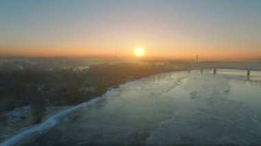  4k hava. Donmuş şehir nehir ve köprü Sunrise, gün batımı ile kış manzarası.