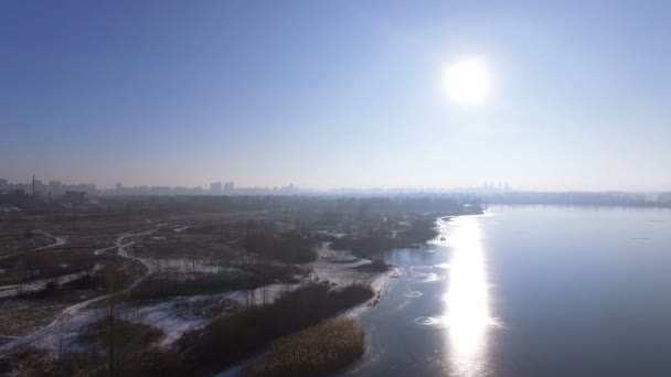 4K Aerial. Зимний пейзаж с замерзшей рекой и отражением солнца в воде — стоковое видео