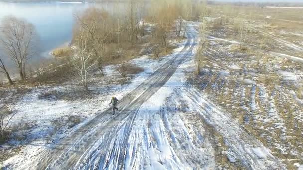 4K Aerial.  Tourist  winter life. Man with  backpack goes  on  frozen road . Panorama — Stock Video