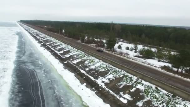 4K Aerial.  Alone car on  winter road near  frozen sea and wood — Stock Video