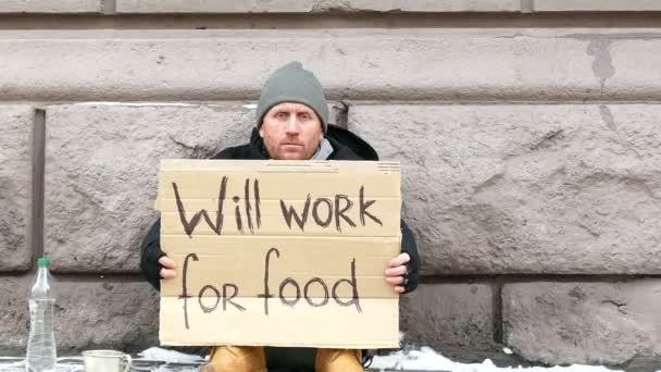 4K. Desespero de pobreza.Homem com papelão, na rua da cidade de inverno. Abordagem do foco — Vídeo de Stock