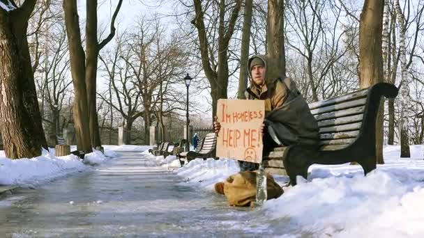 4k. Mladý bezdomovec s karton v zimě městského parku. Změna zaměření — Stock video