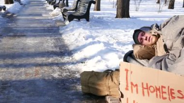   4k. Karton kış Şehir Parkı içinde olan genç adam. Evsiz hayat kaymak vurdu