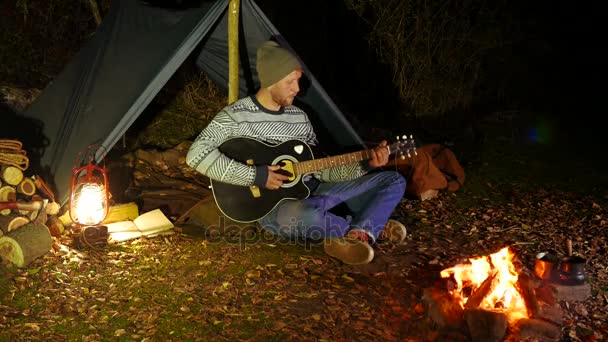 4K. Vida turística. Jovem, viajante, perto da fogueira melodias guitarra — Vídeo de Stock