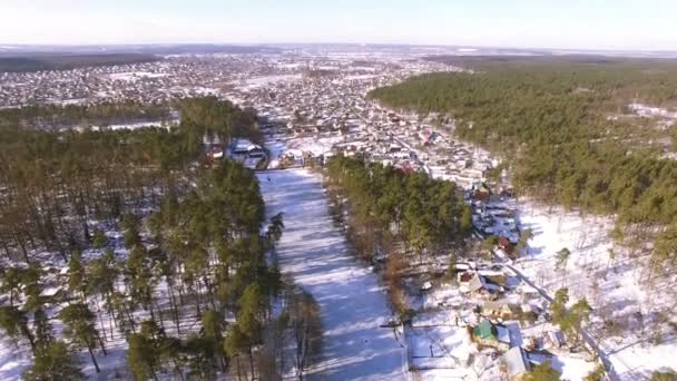 4k luchtfoto. Vliegen met het kantelen van de camera naar beneden over bevroren meer met huizen — Stockvideo