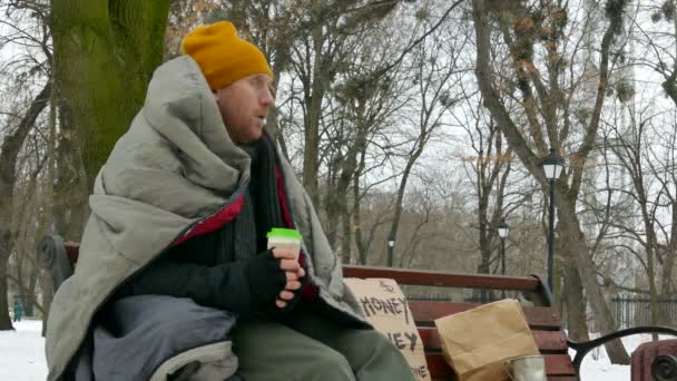 4K. Povero senzatetto adulto sulla panchina della città invernale bere caffè, tè — Video Stock