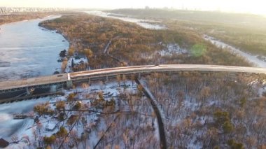  4k hava. Donmuş kış nehir üzerinde sinek ve şehir banliyösünde köprü. Yanal uçuş