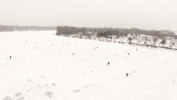 Aérea 4K. Sobre el río helado con los pescadores en el día nublado de invierno. Reducción de la cámara — Vídeos de Stock